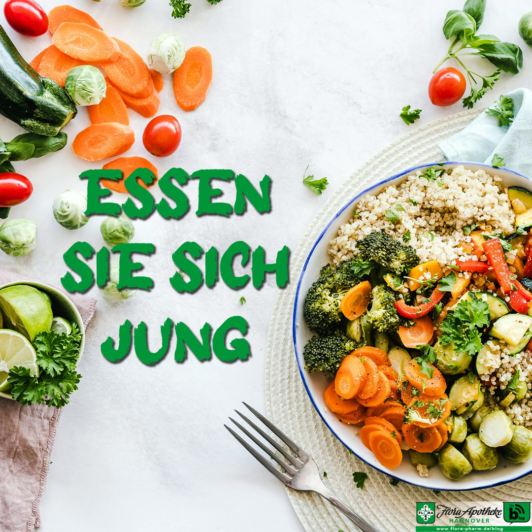 Im Bild liegen verschiedene Gemüse auf einem Tisch um eine Gemüse-Bowl. Zu lesen ist der Schriftzug: 'Essen sie sich jung'