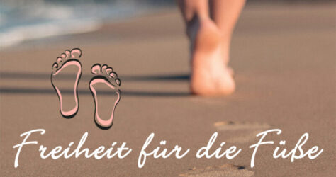 Freiheit für die Füße, dargestellt durch Füße, die am Strand im feuchten Sand spazieren - Barfußlaufen ist im Trend