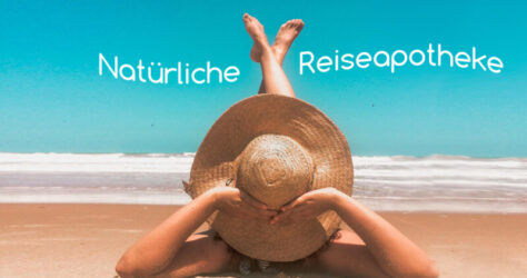 Eine Frau, von der nur Strohhut und Füße sichtbar sind, liegt am Strand in der Sonne. Der Text im Bild sagt: Natürliche Reiseapotheke