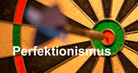 Ein Dartpfeil steckt in der Mitte des Bullseye als Visualisierung von Perfektionismus - erstrebenswert oder zu viel