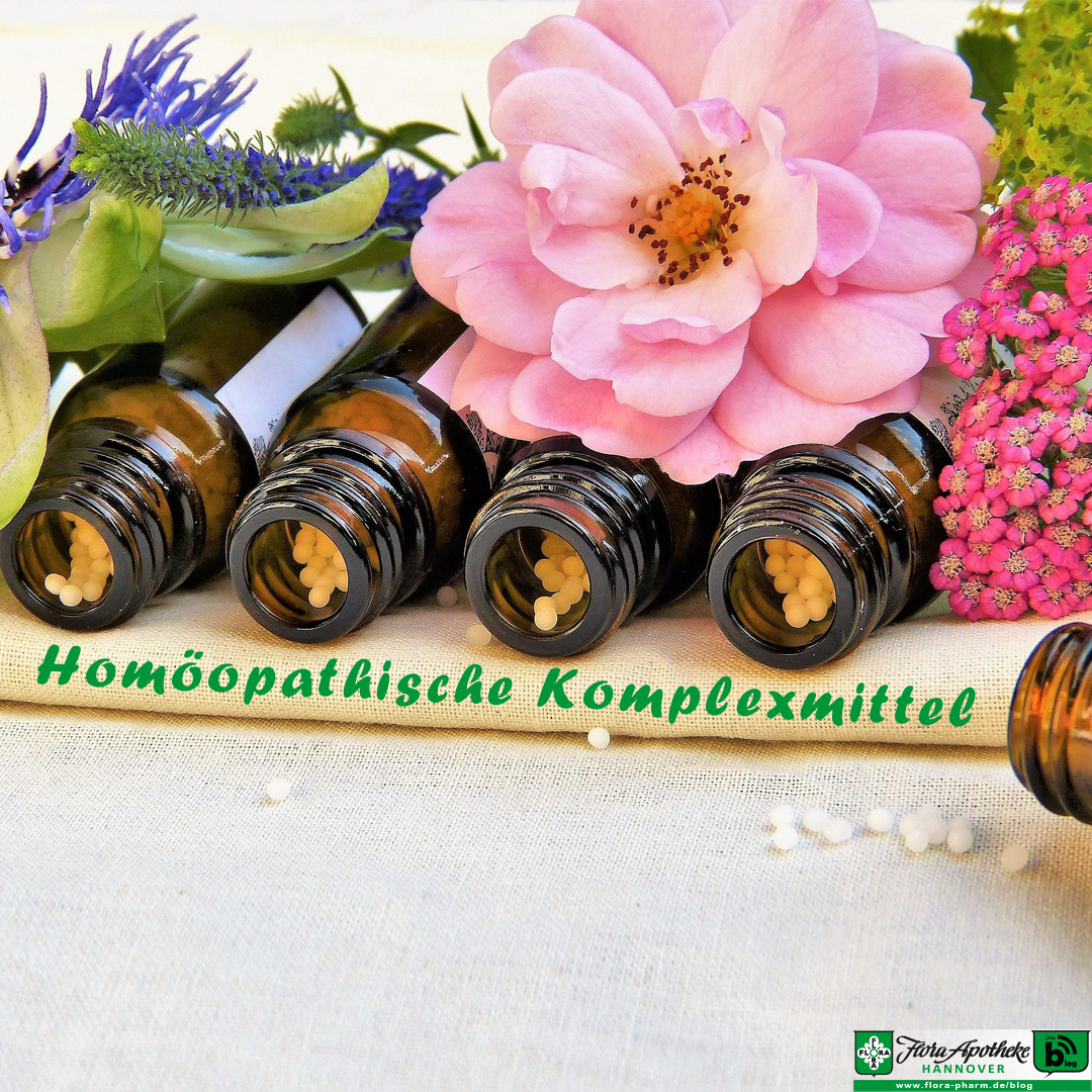 Homöopathische Komplexmittel sind Tausendsassas. Zur Verbildlichung, dass hier mehrere Einzelmittel zusammengefasst wirken, liegen mehrere Globuliflschchen geöffnet nebeneinander unter Blüten auf einem Tuch